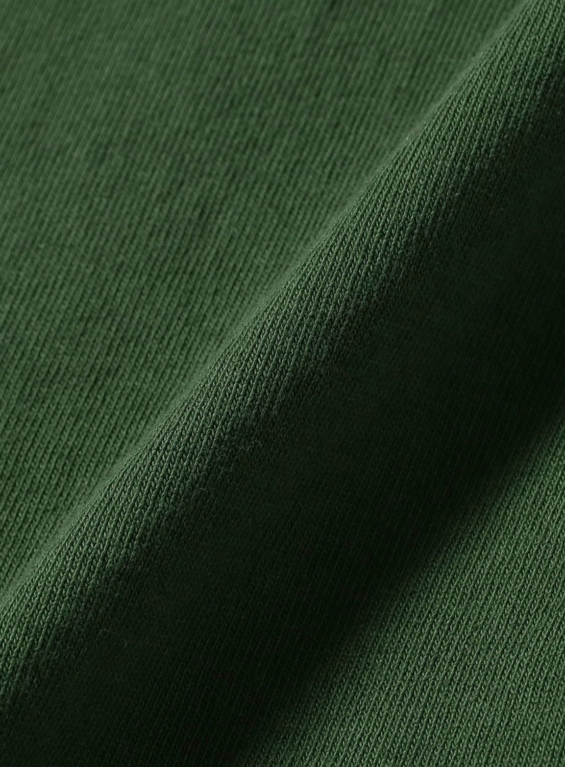 Close-up of dark green ribbed fabric with a diagonal fold, highlighting texture and weave as seen on the dugudagii T-shirt from BEAMS T.