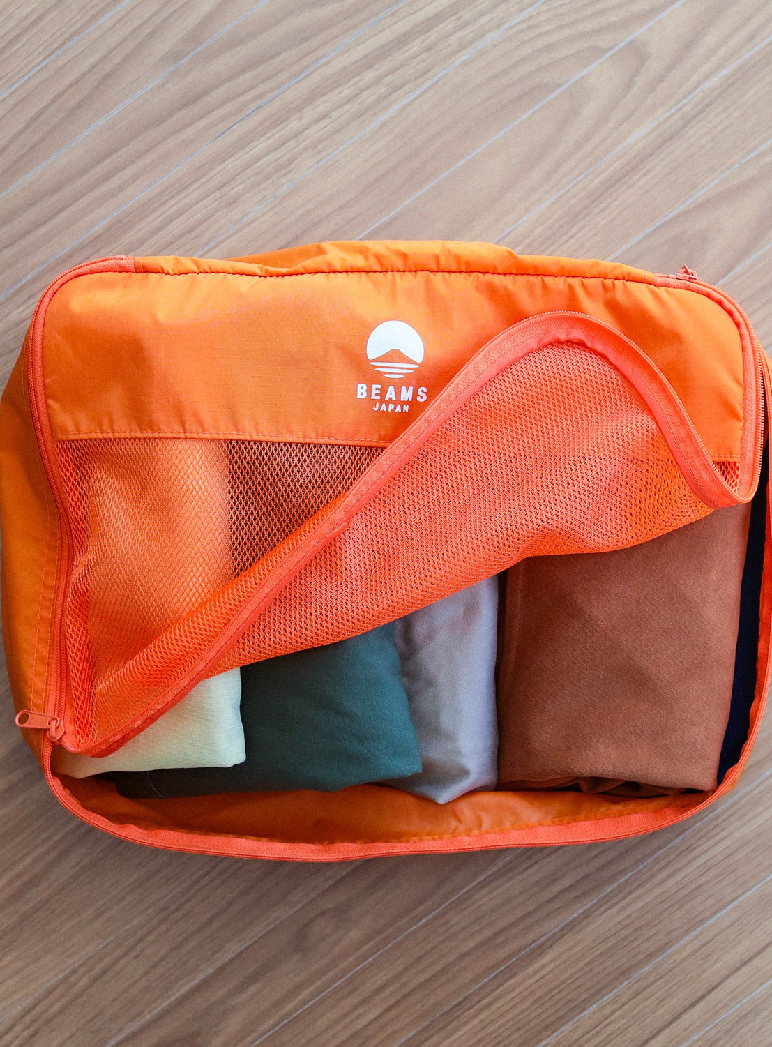 Orange packing cube with clothes inside on a wooden surface