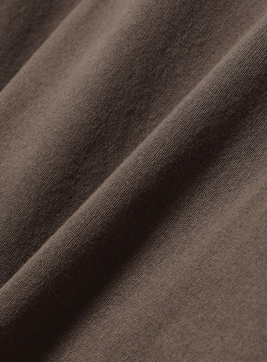 Close-up of a brown heavyweight cotton jersey Garment-Dyed Rugby Shirt featuring a diagonal fold.