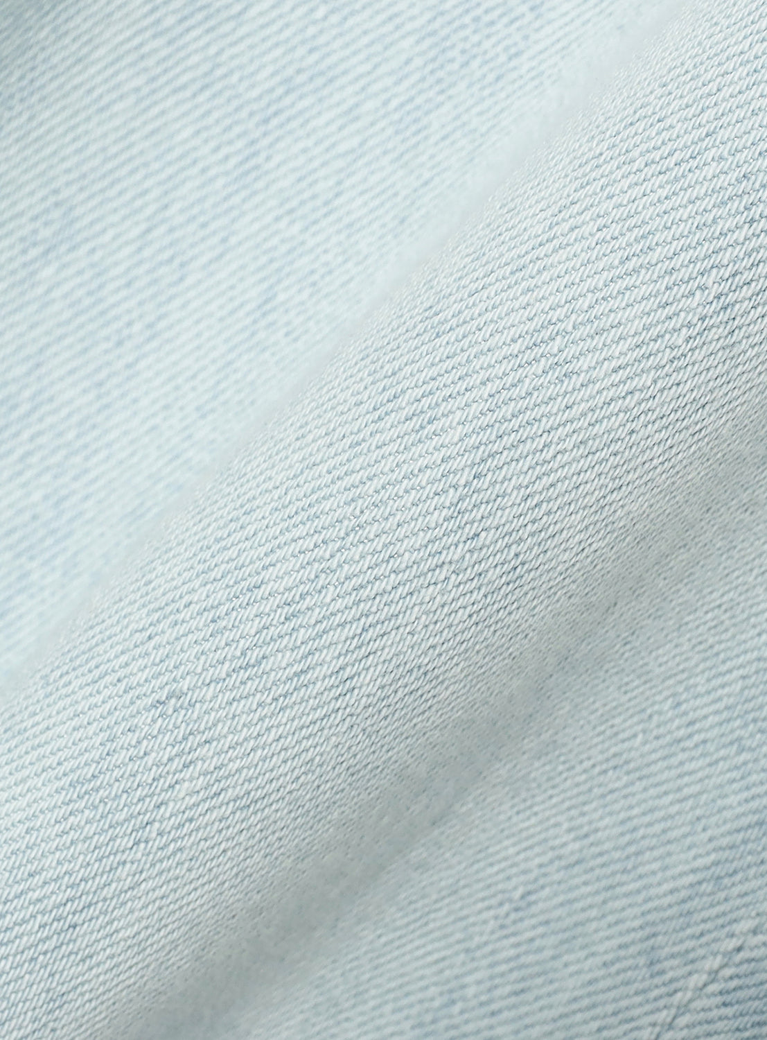 Close-up of light blue Wide Denim Slacks, showing the detailed twill weave of the fabric.