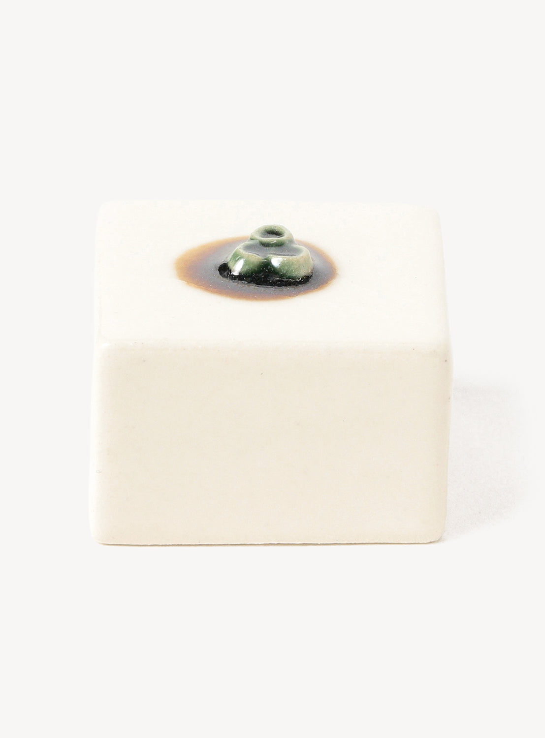 White hexagonal chopstick rest with a small black and brown design on a white background