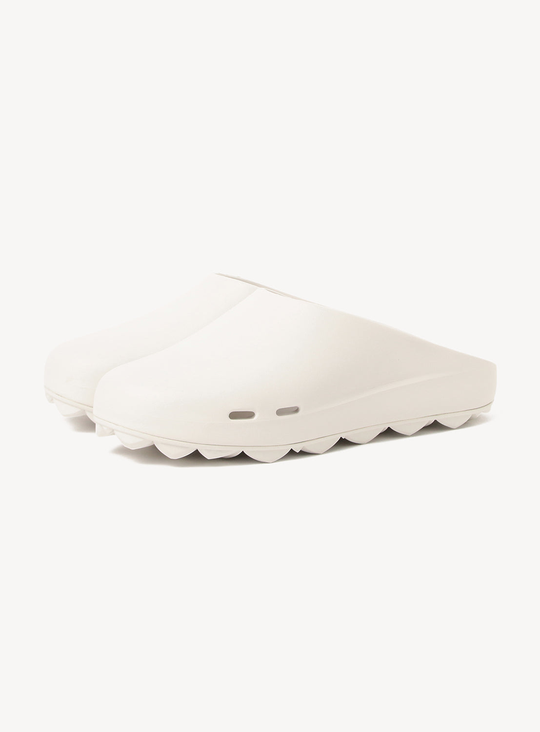 The PPACO LUX-1 Closed-Toe Slide Sandals are white, slip-on clogs with a minimalist design, thick wavy soles, cushioned construction, and small rectangular ventilation holes near the arch.