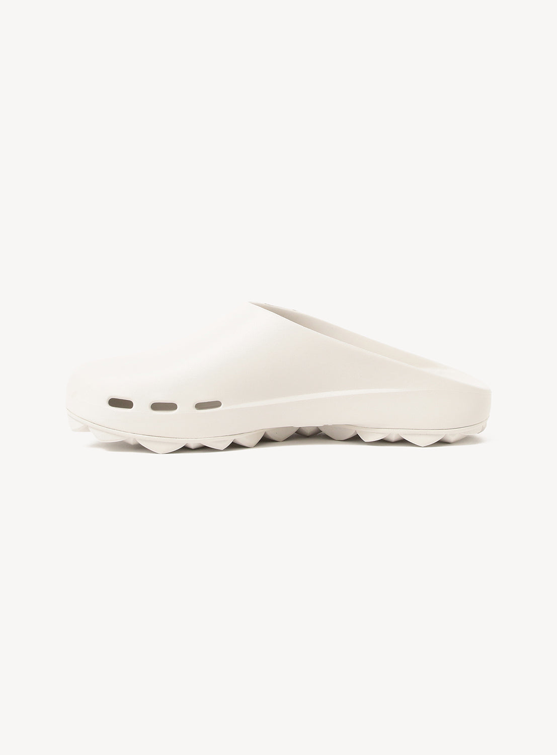 The PPACO LUX-1 Closed-Toe Slide Sandals feature a minimalist white slip-on design with a smooth, rounded upper, three toe ventilation holes, and a thick, wavy-textured sole for lightweight comfort, shown in side profile on a white background.