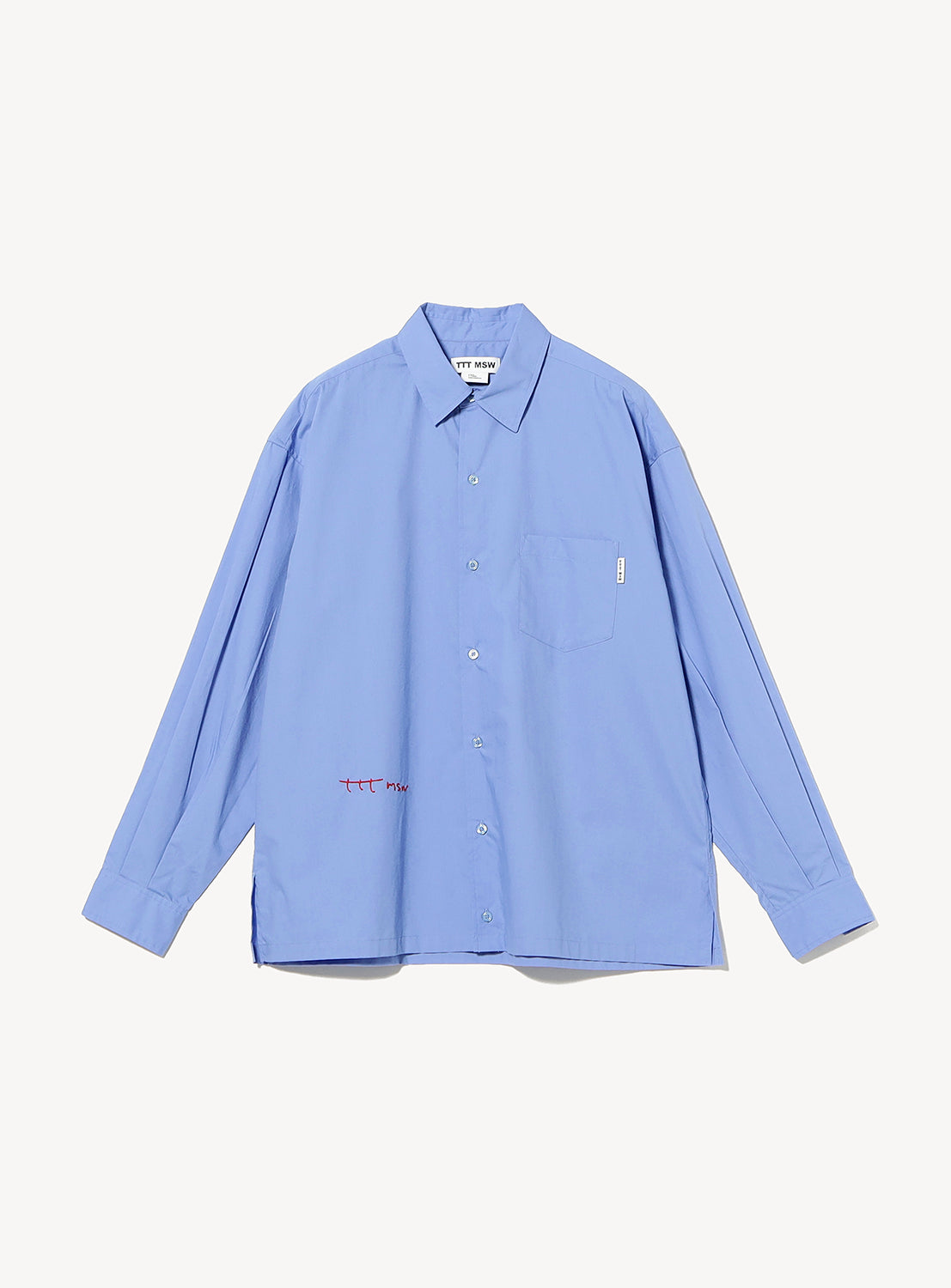 The TTT MSW Regular Collar Shirt, a light blue genderless design, features long sleeves, a button-up front, and a classic collar with a chest pocket. Subtle red and white stitching accents near the pocket and lower hem add modern detail to its timeless silhouette. Shown laid flat on a white background.