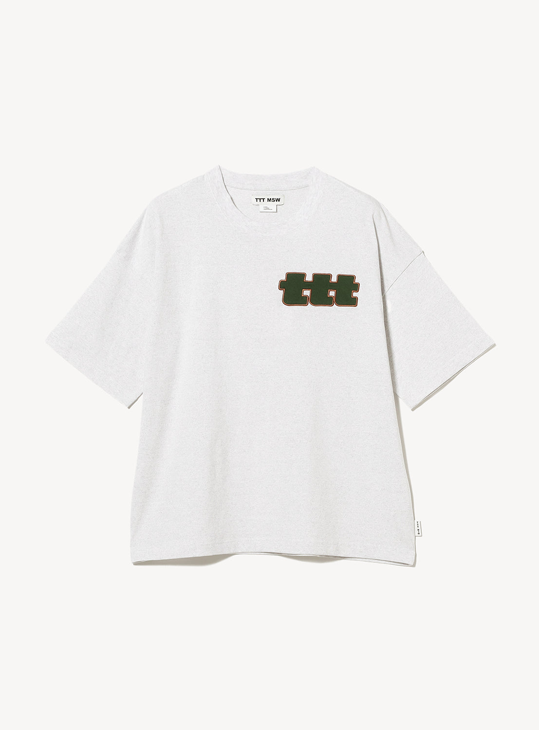 The TTT MSW Logo T-Shirt by TTT MSW is an oversized plain white shirt made from 100% cotton, showcasing the bold Triple T logo in dark font on the left chest.