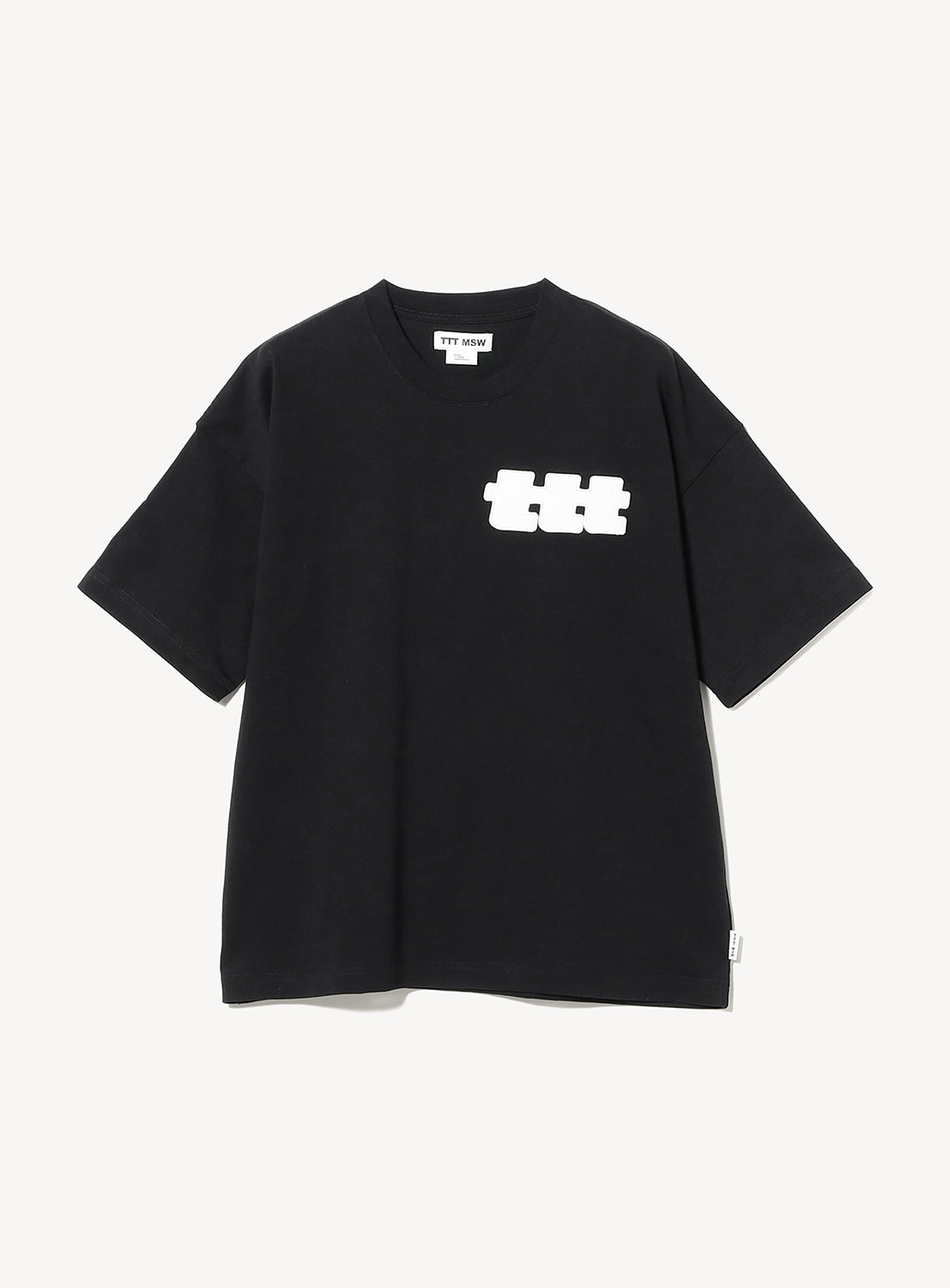 The TTT MSW Logo T-Shirt by TTT MSW is a plain black short-sleeve tee, embroidered with the signature Triple T logo in white on the left chest. The shirt is displayed laid flat on a white background.