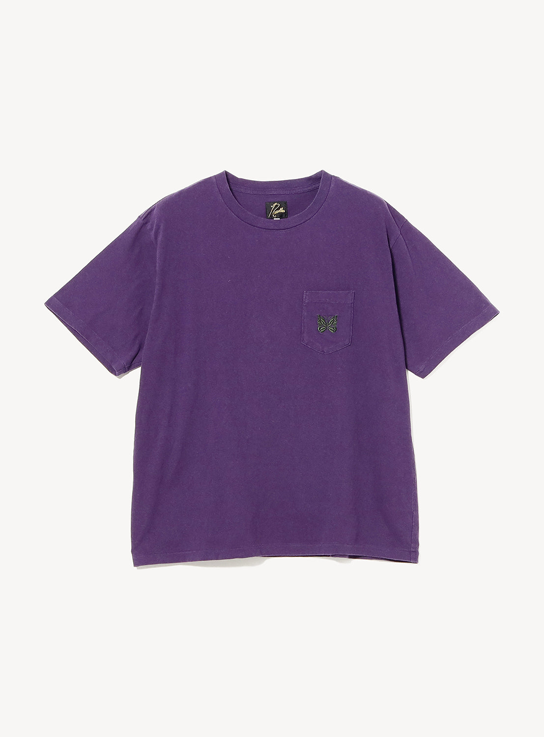 Front view of a purple crew neck T-shirt with a relaxed fit. Features a chest patch pocket accented with NEEDLES' signature embroidered Papillon butterfly logo in contrasting green and black, creating a clean, minimalist look.