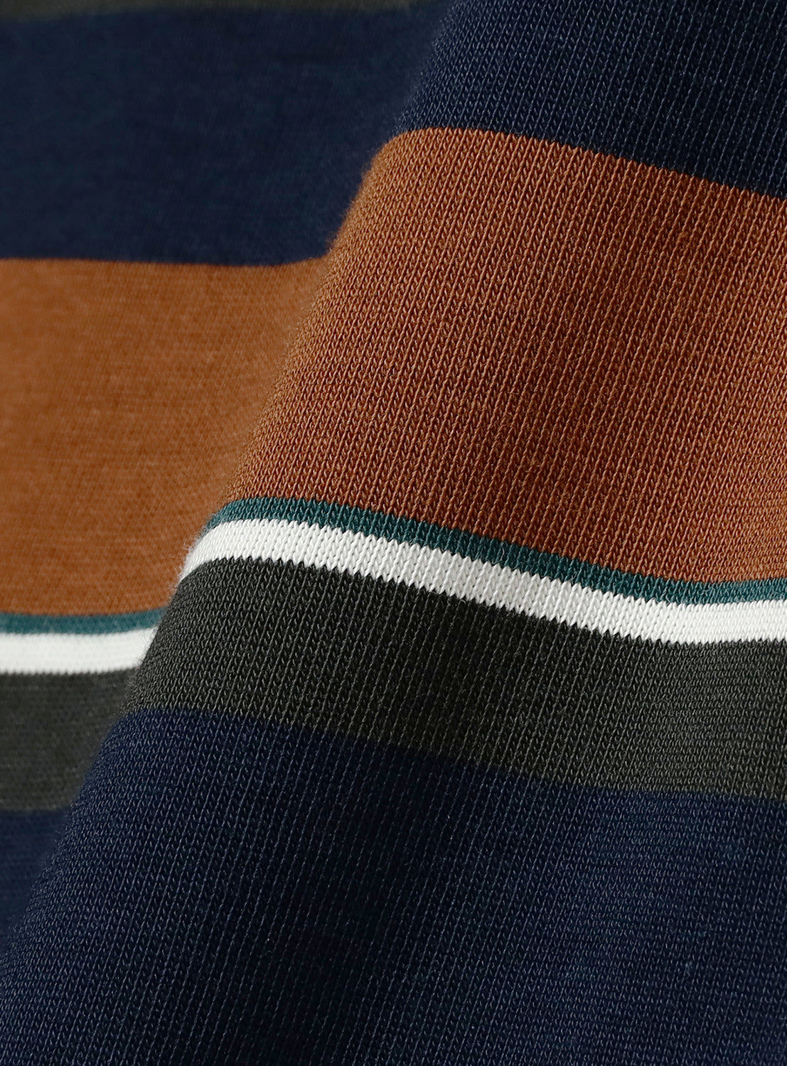 Close-up of the BEAMS Multi-Border T-Shirt fabric, featuring horizontal stripes in navy blue, brown, dark green, white, and teal. The 100% cotton surface displays a gentle fold that emphasizes the texture and distinctive multi-colored border stripe pattern.