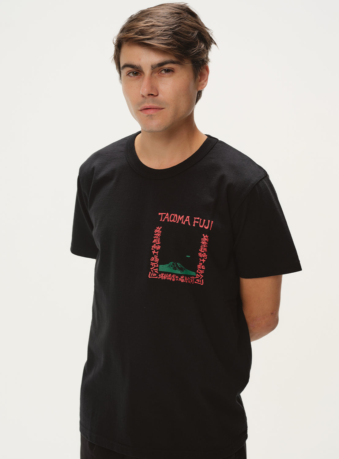 Model wearing a black t-shirt with red "TACOMA FUJI" graphic, front view, displaying the shirt's fit.