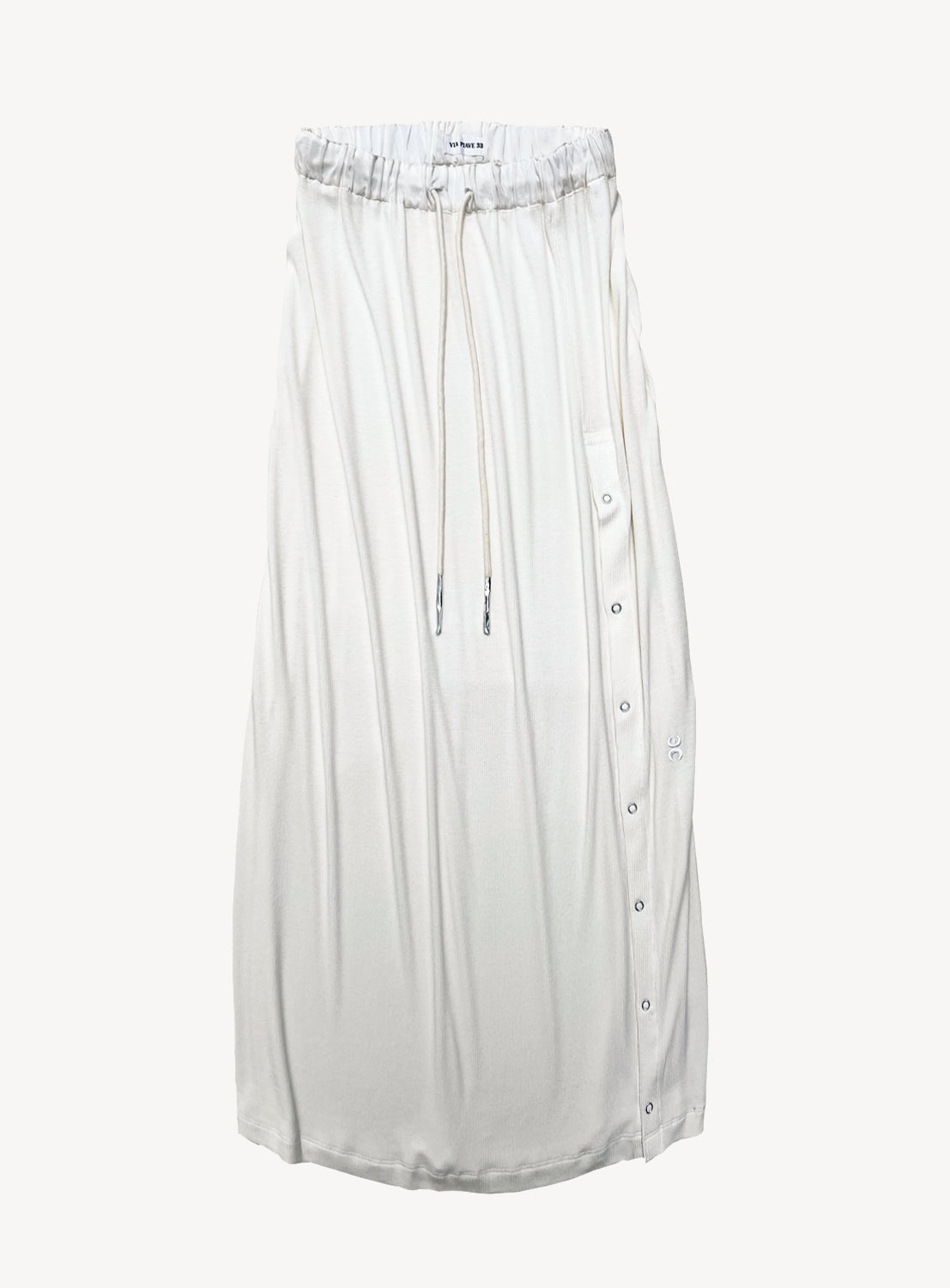 The VIAPIAVE33 Bamboo Rib Skirt is a white midi skirt with a relaxed straight silhouette, designed with an elastic drawstring waistband and accented by a row of buttons along one side. Crafted from lightweight, soft, and airy fabric, the skirt is displayed against a plain white background.
